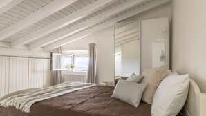 Quarto com cama grande, janela com cortinas, radiador e espelho.