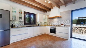 A modern kitchen with white cabinets, a built-in oven, and a large window. - Can Pere Xine, Mallorcan Charm near Cala Mondragó (santañy)