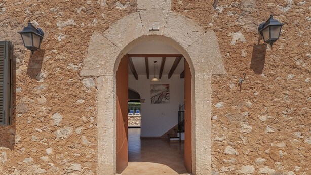 An arched doorway leading into a building with stone walls and two wall-mounted lanterns. - Can Pere Xine, Mallorcan Charm near Cala Mondragó (santañy)
