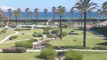 A landscaped garden with palm trees, a pool, and a tennis court.