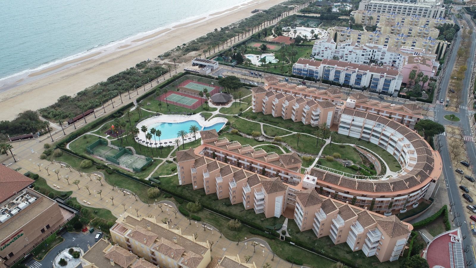 Een kusthotel met een centrale binnenplaats, een zwembad en uitzicht op het strand.