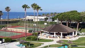 A sports court with a tennis court, a pavilion, and outdoor seating with umbrellas. - Islantur Las Américas (Isla Cristina)