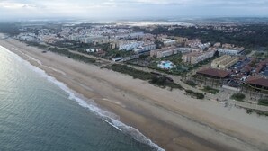 An aerial view of a coastal area with a beach, residential buildings, and a large hotel complex. - Islantur Las Américas (Isla Cristina)