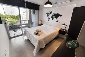 A modern hotel room with a large bed, a world map on the wall, a balcony with a chair, and a potted plant. - Bonpland & Nicaragua Studio (Buenos Aires)