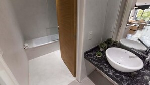 A modern bathroom with a bathtub, two sinks, and a large mirror.