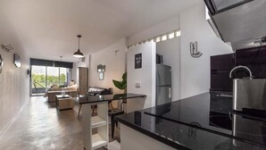 A modern kitchen with a black countertop, stainless steel appliances, and a glass backsplash.