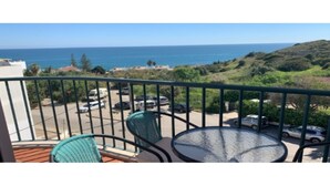 A balcony with two chairs and a table, overlooking a parking area and a view of the sea and hills. - SAINT JAMES - APT SEA VIEW - 2 / 4PERS (Luz)