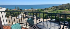 A balcony with two chairs and a table, overlooking a parking area and a view of the sea and hills. - SAINT JAMES - APT SEA VIEW - 2 / 4PERS (Luz)