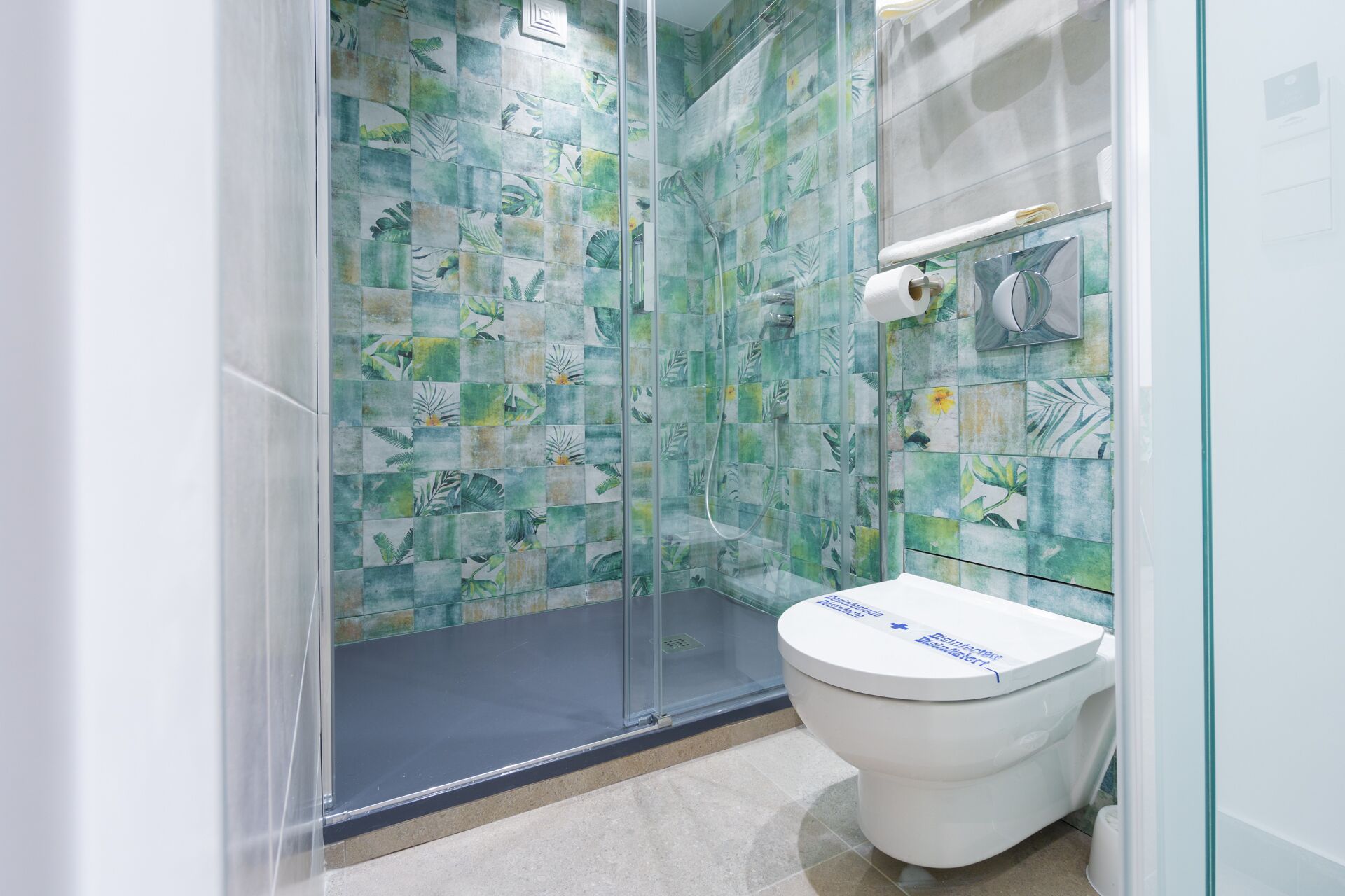 Een badkamer met een douchecabine van glas en een toilet met een blauw label.