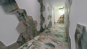 A hallway with hexagonal patterned tiles and wall art. - Hostal Restaurante Pou Des Lleó (Santa Eulalia del Rio)