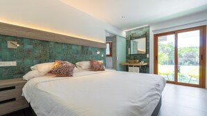 A modern bedroom with a large bed, a wooden headboard, a built-in bench, a bathroom with a sink and mirror, and a sliding glass door to an outdoor area. - Hostal Restaurante Pou Des Lleó (Santa Eulalia del Rio)