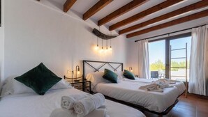 A hotel room with two beds, white linens, green pillows, a wooden ceiling, and a view through a large window. - Hostal Restaurante Pou Des Lleó (Santa Eulalia del Rio)