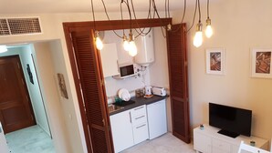 Uma cozinha compacta com micro-ondas, torradeira e pia.
