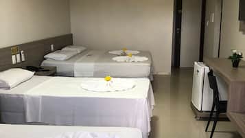 A hotel room with two beds, a desk, a refrigerator, and a door leading to another room.