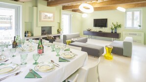 A dining area with a table set for a meal, a sofa, and a television in the background. - Villa for 10 People with WiFi, Private Pool, Garden, A/C, near Lucca (Vorno)