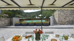 An outdoor dining area with a table set for a meal, surrounded by stone walls and a view of a mountain. - Villa for 10 People with WiFi, Private Pool, Garden, A/C, near Lucca (Vorno)