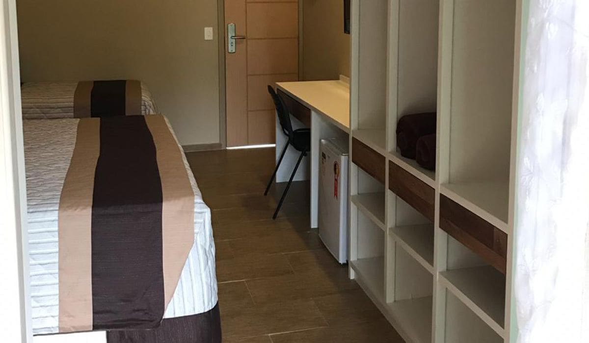 A hotel room with a bed, a desk, and a wardrobe.