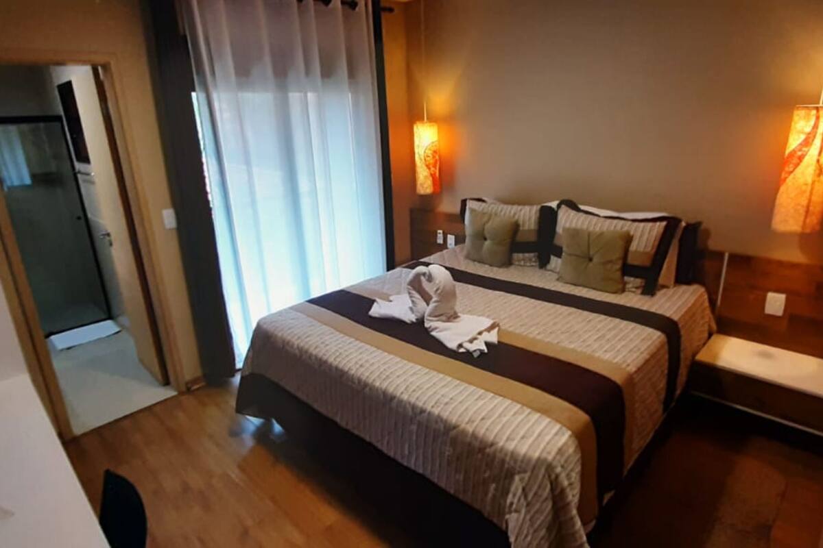 Une chambre d’hôtel avec un lit, des lampes de chevet, une porte et une vue sur un couloir.