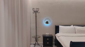 A bedroom with a bed, a nightstand, a floor lamp, and a wall-mounted light fixture.