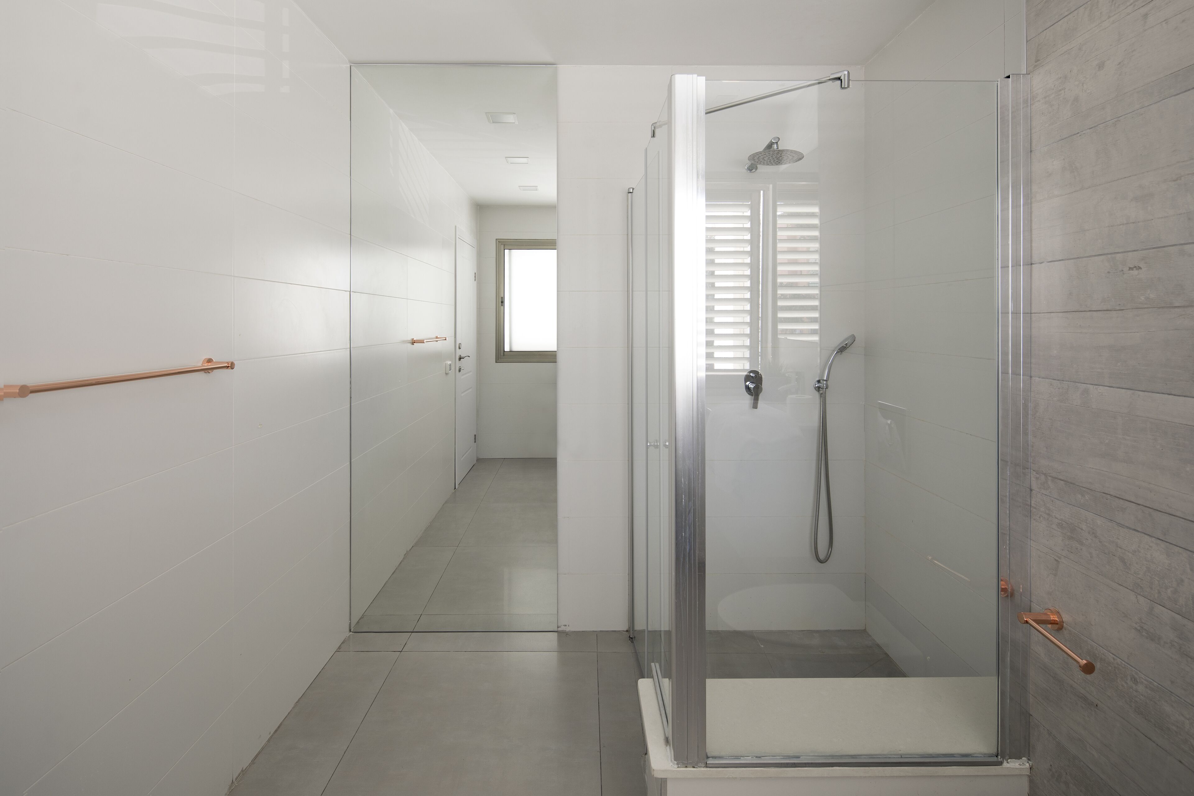 Een moderne badkamer met een douchecabine van glas, witte betegelde wanden en een houten vloer.