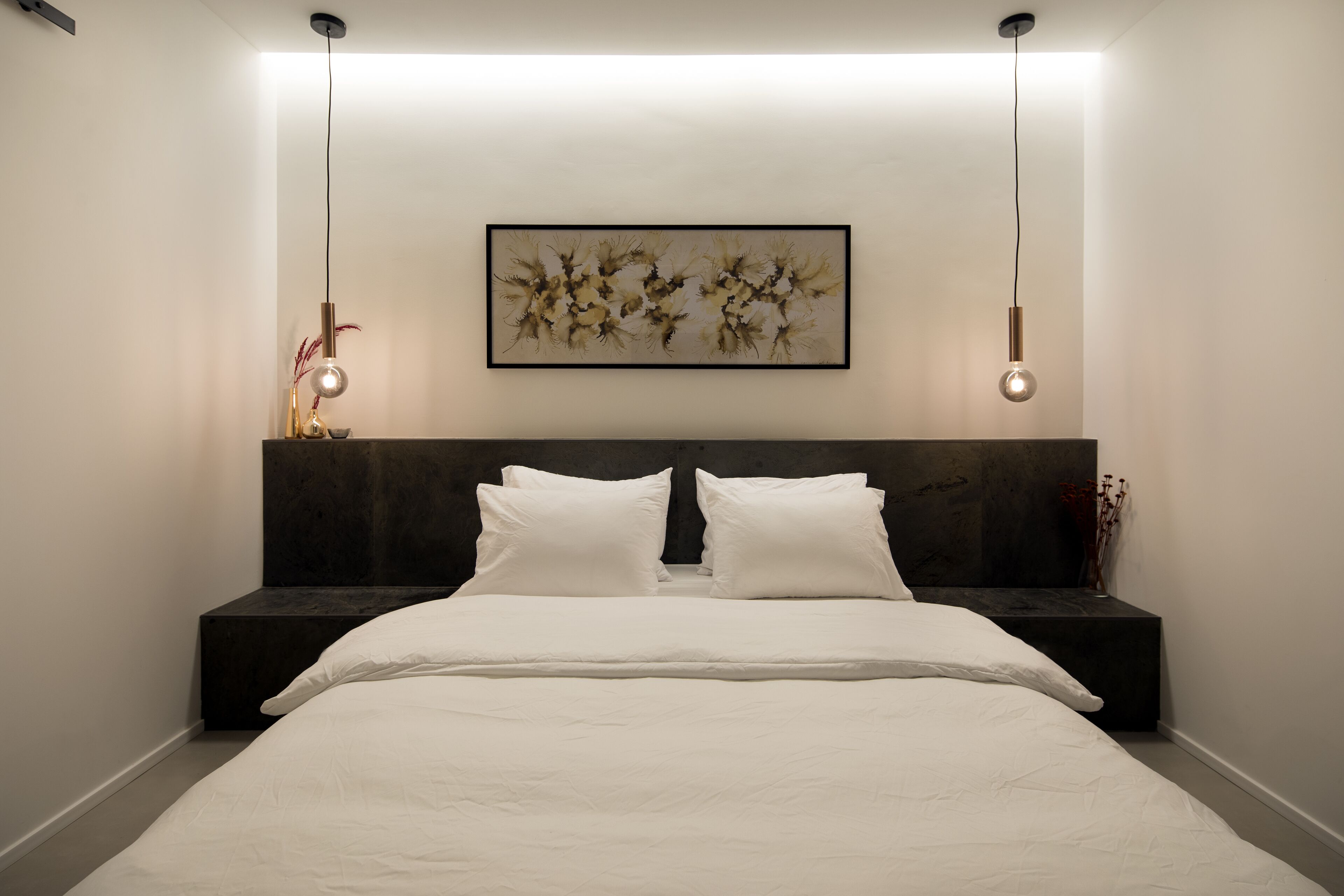 A modern bedroom with a large bed, a dark headboard, and a framed artwork above it.