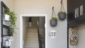Um corredor com escadas que levam a outro andar, plantas em vasos e uma câmera de segurança.