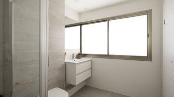Un baño moderno con cabina de ducha de vidrio, inodoro blanco, lavabo con espejo sobre él y ventana que proporciona luz natural.