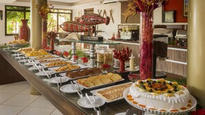 Un buffet proposant une variété de plats, notamment des gâteaux et des pâtisseries, disposés sur une longue table.