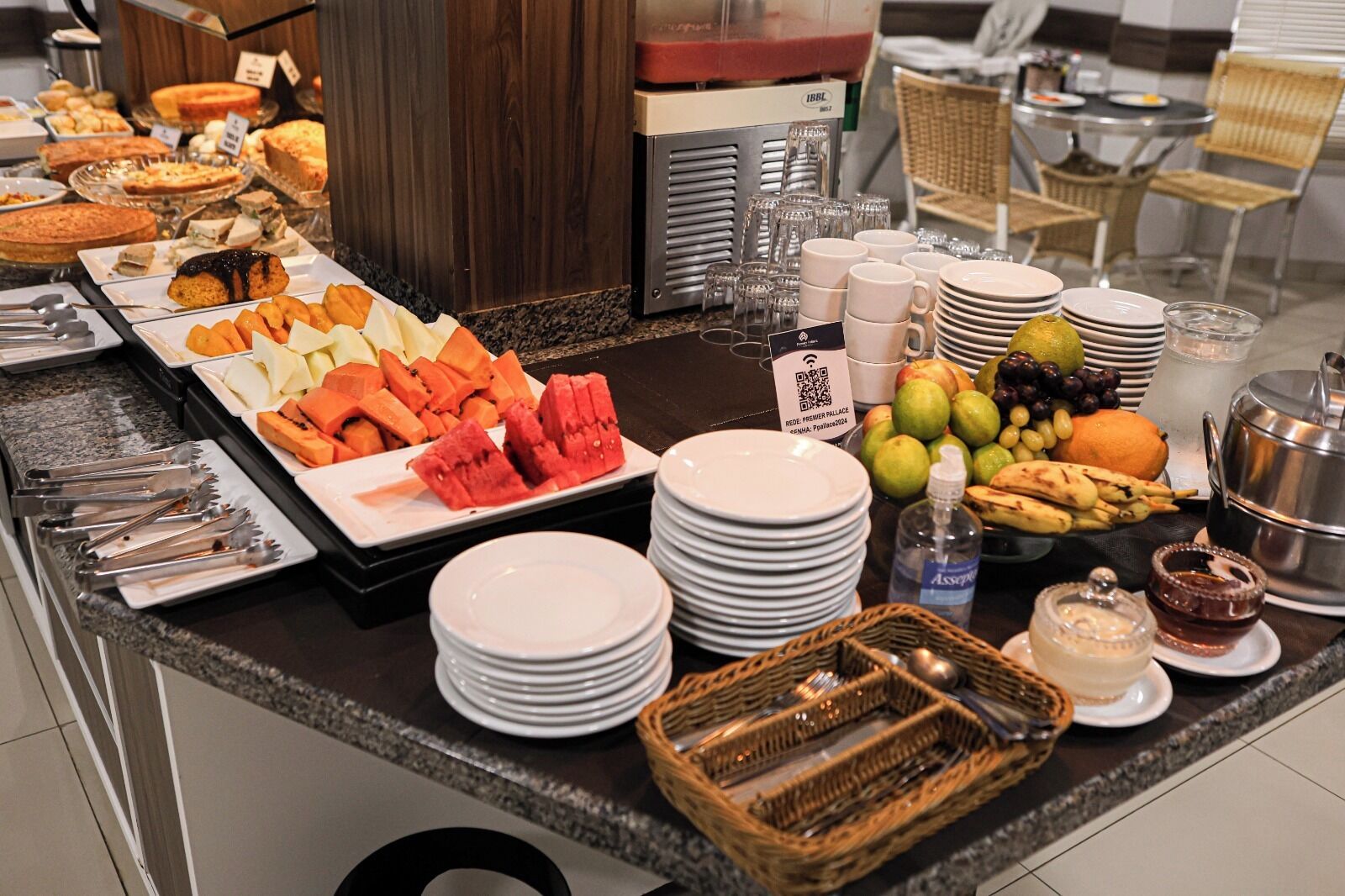 A buffet with various fruits, pastries, and a coffee machine.