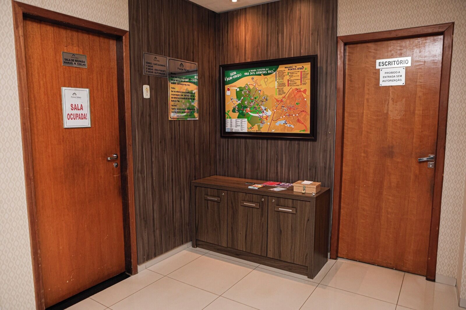 A hallway with wooden doors, a reception desk, and a map on the wall.