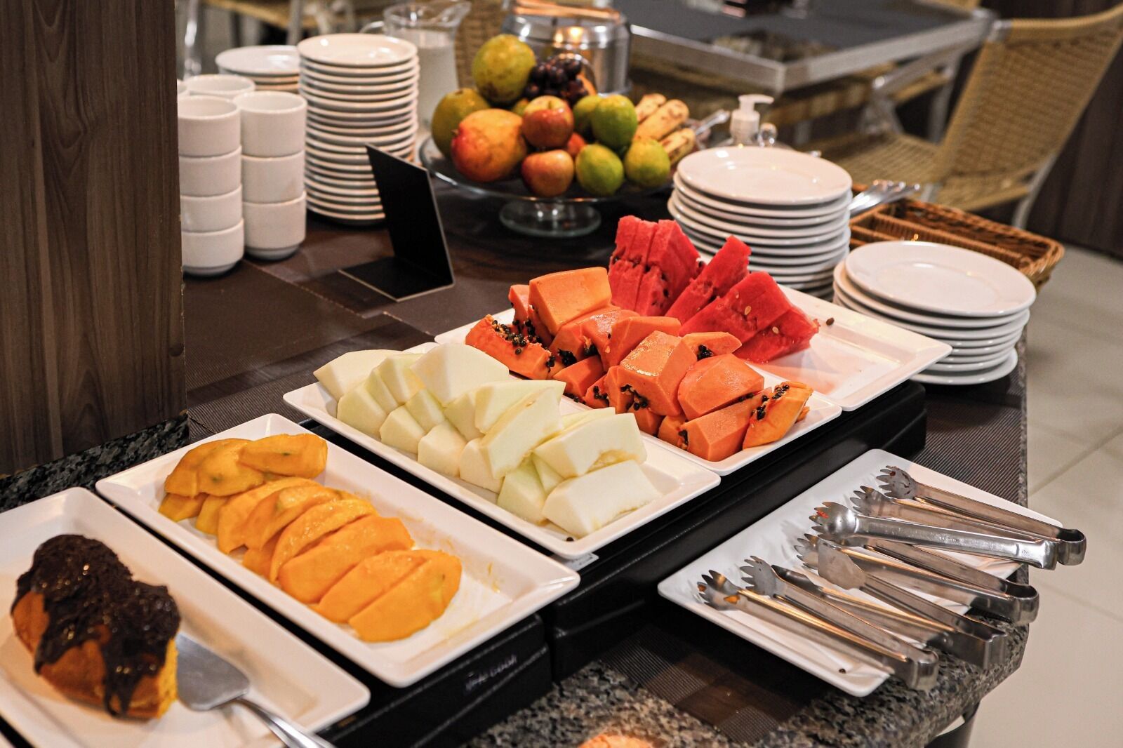 Een buffet met verschillende soorten fruit en een assortiment bestek.