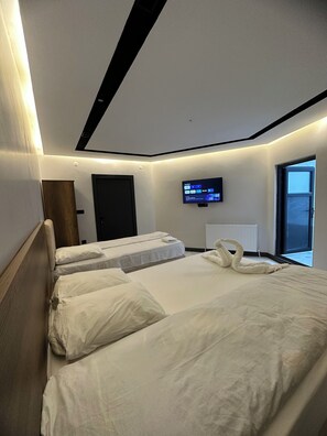 A hotel room with two beds, a TV on the wall, and a window. - Antik Otel (Havza)