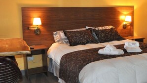 Hotellihuone, jossa on suuri sänky, kaksi yöpöytää, tuoli ja vaatekaappi.