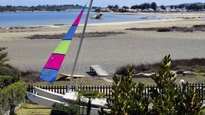 Una playa con un velero y una vela colorida.