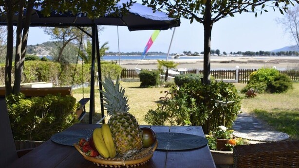 Una mesa con frutero, asientos al aire libre y vista a la playa y montañas.