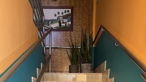 A staircase with a handrail, leading to a landing with a framed picture and potted plants. - Pousada Ferreira (Aracaju)