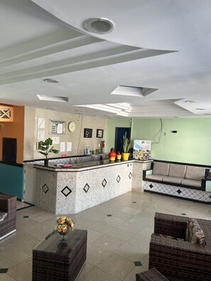 Un área de recepción con mostrador, asientos y una pared con carteles informativos.
