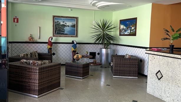 A lobby with a reception desk, seating area, and artwork on the walls. - Pousada Ferreira (Aracaju)