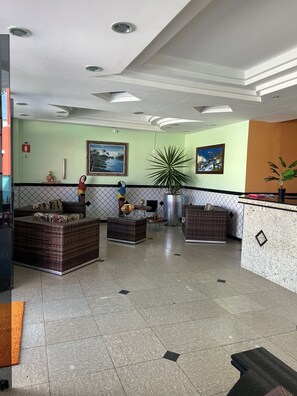 A lobby with a reception desk, seating area, and artwork on the walls.