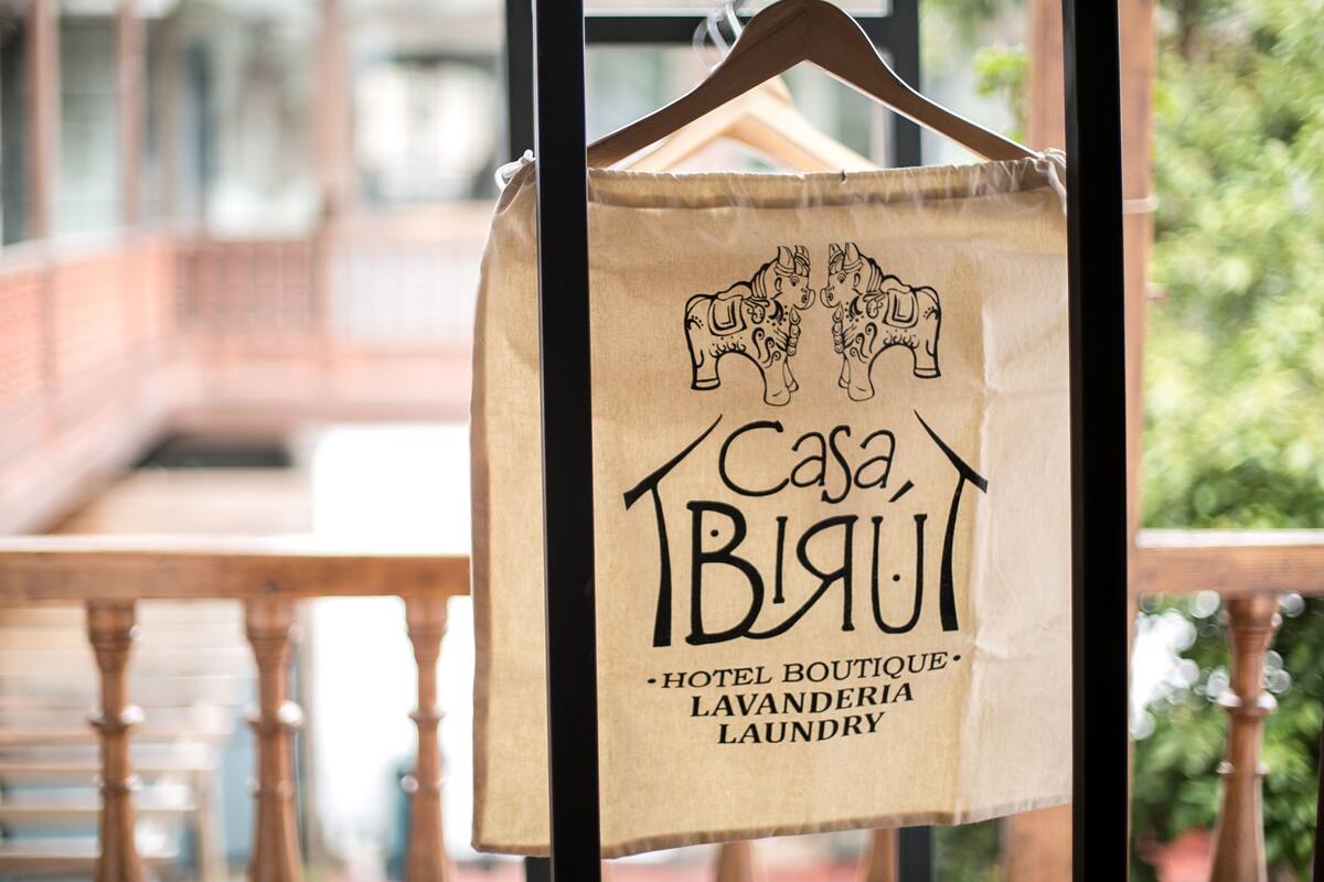 A hanging bag with the text 'Casa Blanca Hotel Boutique Lavandéria Laundry' and a drawing of two horses.