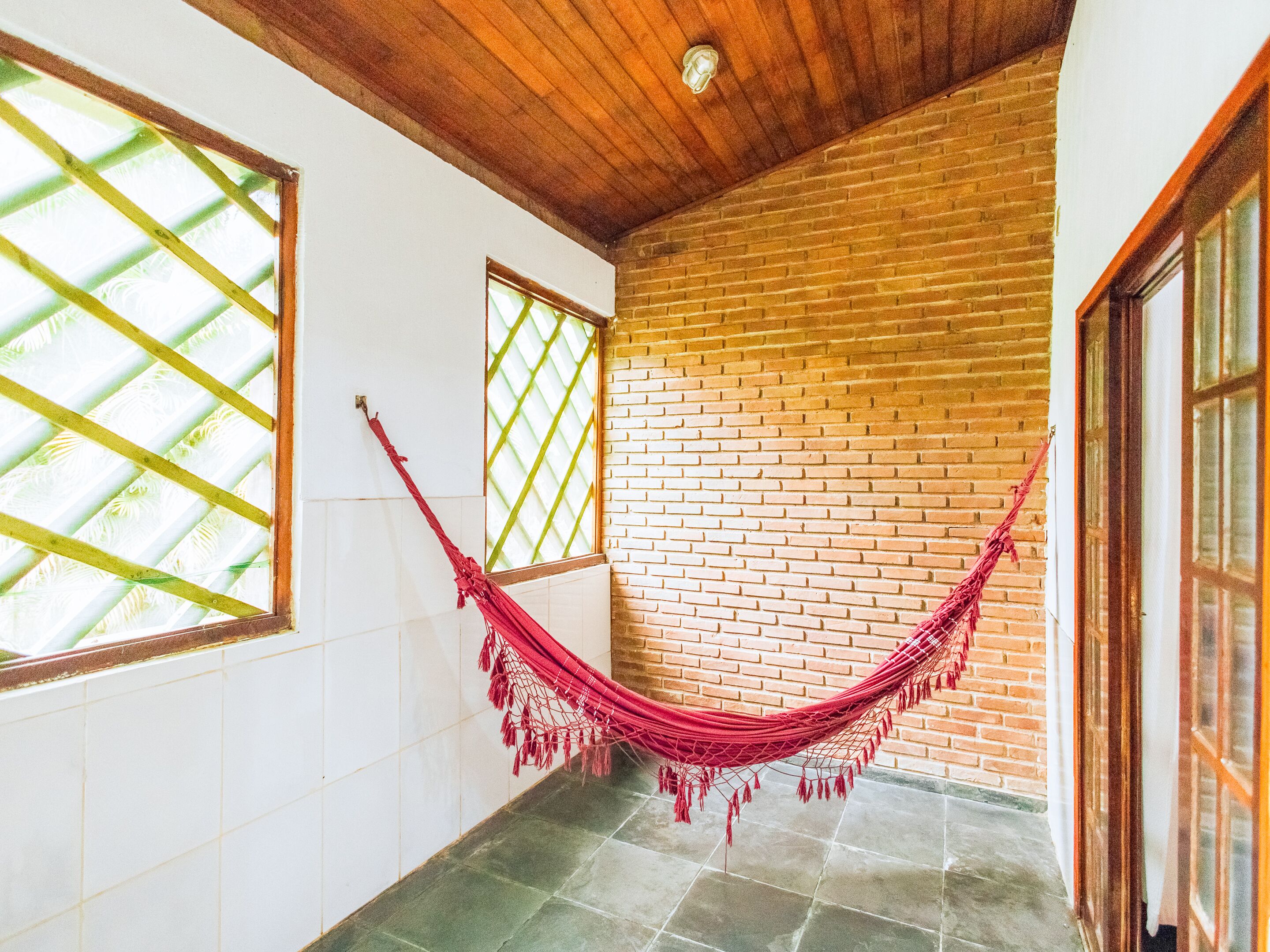 A room with a brick wall, a wooden ceiling, and a hammock.