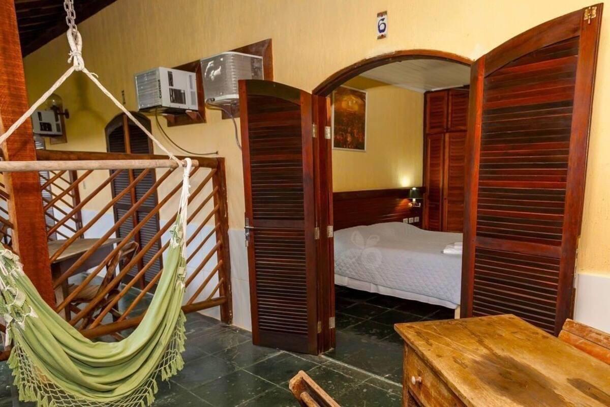 Una habitación con cama, una hamaca, una mesa de madera y una escalera.