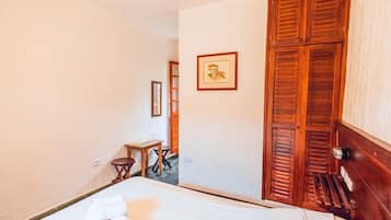 Habitació d'hotel amb un llit, una porta de fusta, una taula petita i un quadre a la paret.