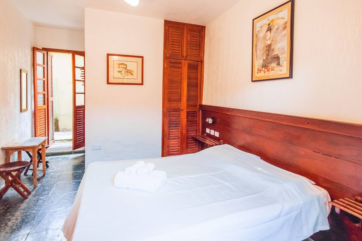 Una habitación de hotel con una cama, un armario de madera y un cuadro en la pared.
