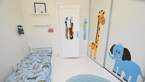 A child's bedroom with a bed, a door, and wall decorations including a giraffe and an elephant. - Solferie Apartment Odins Gate (Kristiansand)