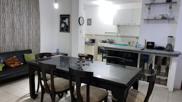 Una sala de estar moderna con una mesa de comedor y sillas, un sofá y una zona de cocina con armarios y electrodomésticos.
