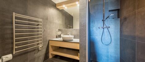 Een moderne badkamer met toilet, wastafel, spiegel en douche.
