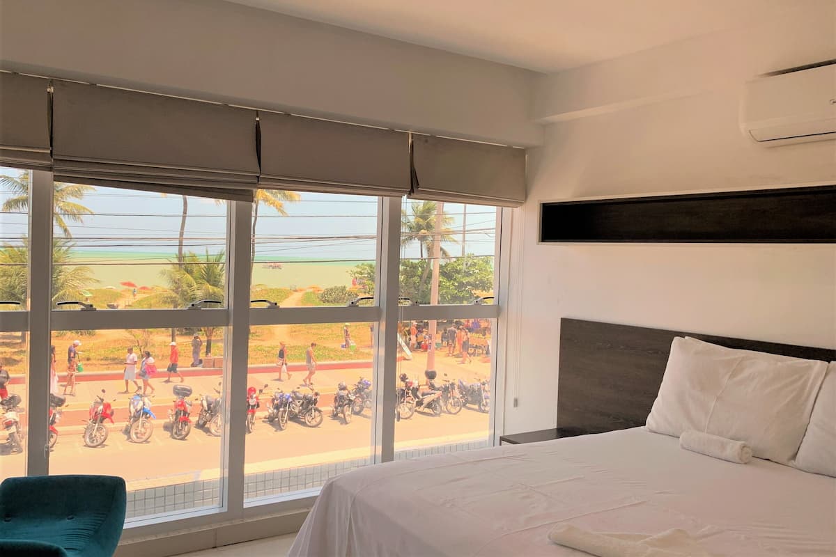 Habitación de hotel con un ventanal grande, una cama, una silla y aire acondicionado instalado en la pared.