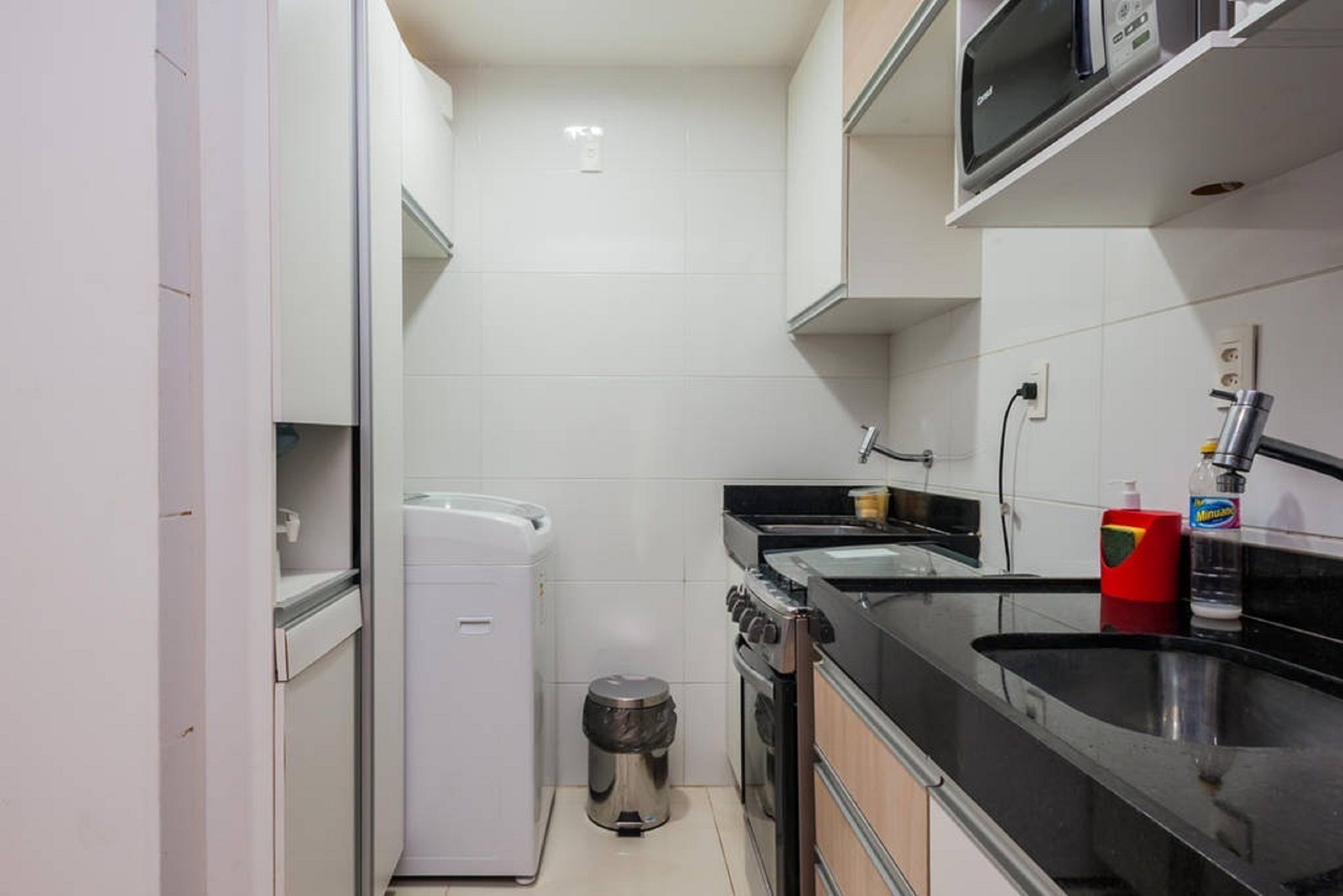 A compact kitchen with a refrigerator, stove, sink, and microwave.
