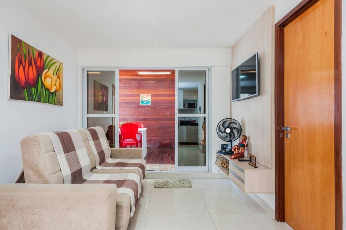 Una sala de estar con un sofá, una butaca roja, un televisor y una pared de madera.